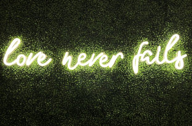 A neon sign for 'Love never fails'