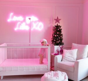 A beautiful photograph of a baby with a pink text on the wall