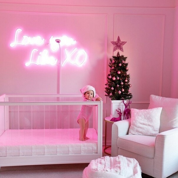 A beautiful photograph of a baby with a pink text on the wall