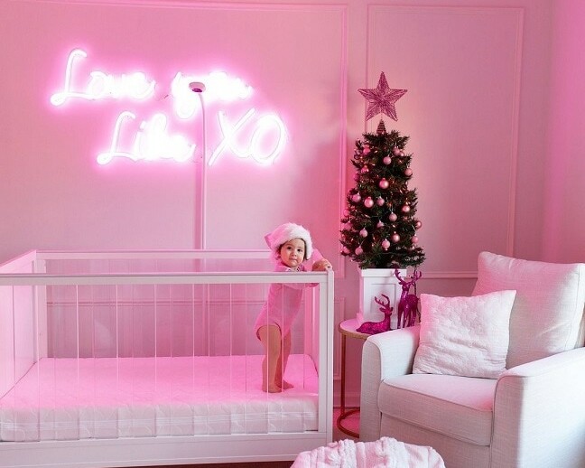 A beautiful photograph of a baby with a pink text on the wall