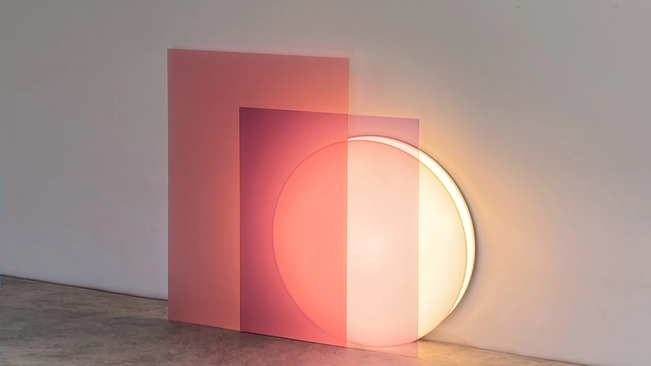 A sleek and modern floor lamp, called Lune, with a curved white base and a thin neon light