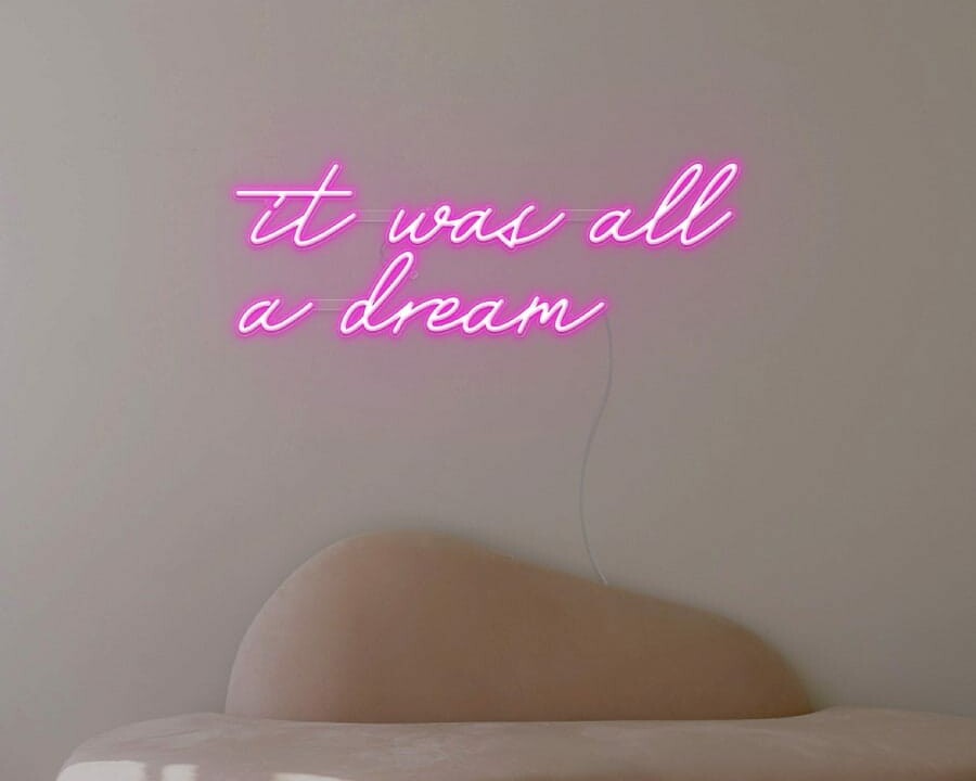 A dreamy neon sign of the phrase 'it was all a dream’ in pink