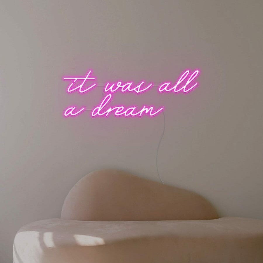 A dreamy neon sign of the phrase 'it was all a dream’ in pink