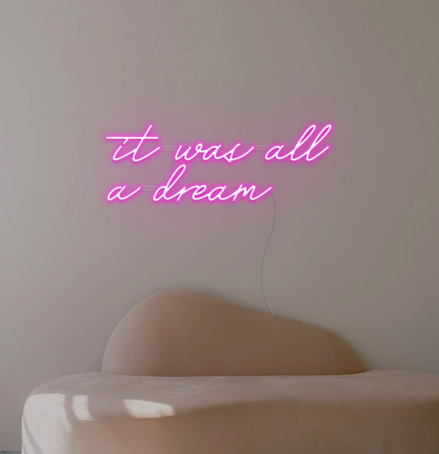 A dreamy neon sign of the phrase 'it was all a dream’ in pink