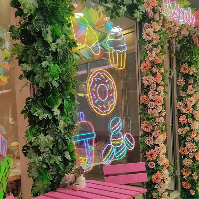 Colorful dessert neon signs with a floral photo backdrop in a sweet shop
