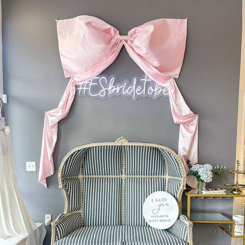 Custom hashtag neon sign beneath a pink bow in a bridal boutique