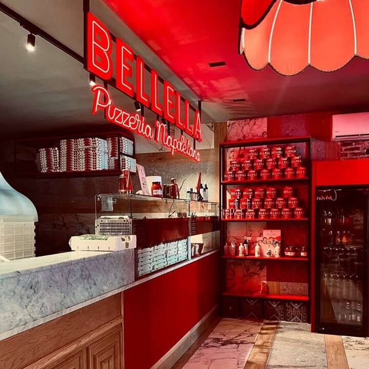 Custom red neon logo sign above a pizza shop counter