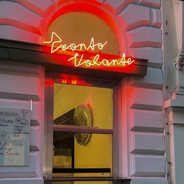 Custom script neon sign for a pizza shop above an arched doorway