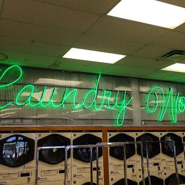 Green custom laundromat glass neon sign in script lettering