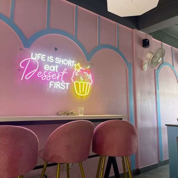 Life Is Short Eat Dessert First neon sign with a cupcake in a dessert shop