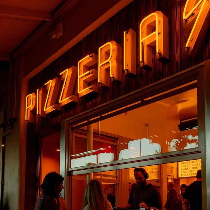 Orange Pizzeria glass neon sign above a pizza shop entrance
