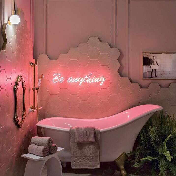 Pink Be Everything neon sign above a freestanding bathroom tub