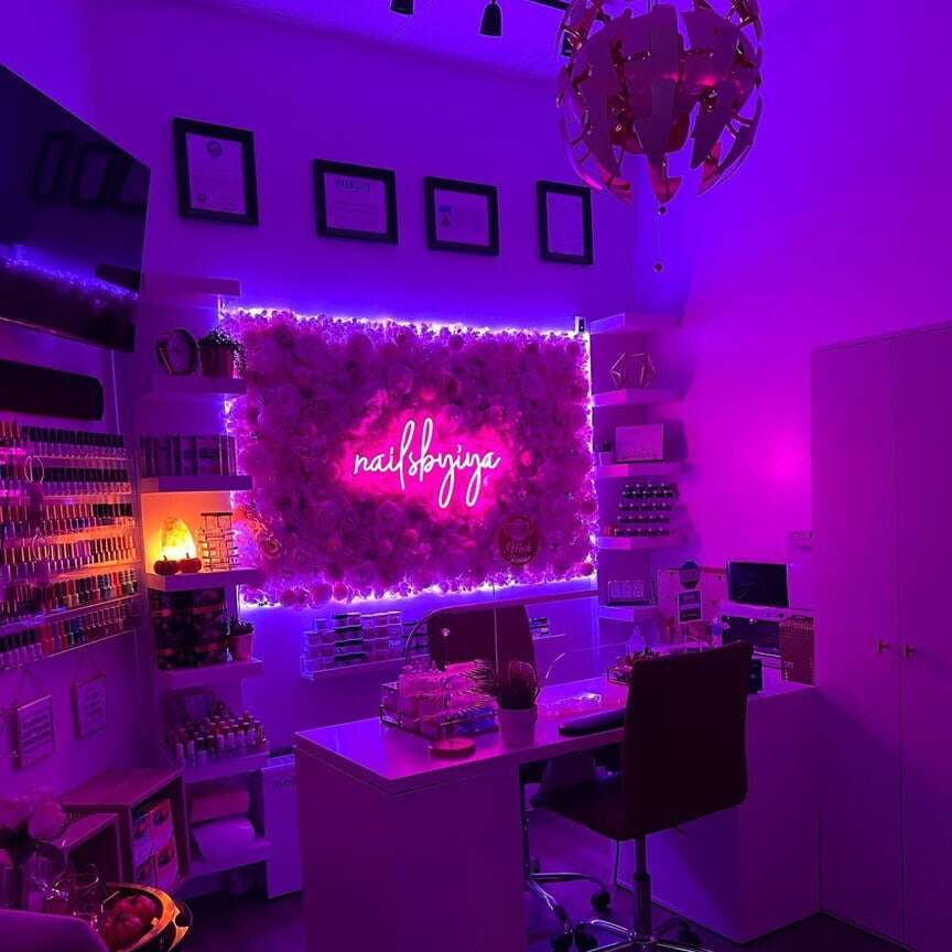 Pink and purple neon nail art sign above manicure stations