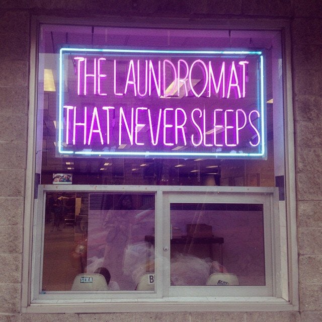Pink laundromat window neon sign with a blue border
