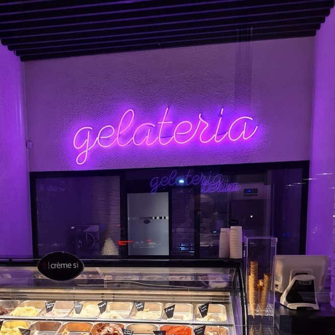 Purple Gelateria neon sign above an ice cream display counter