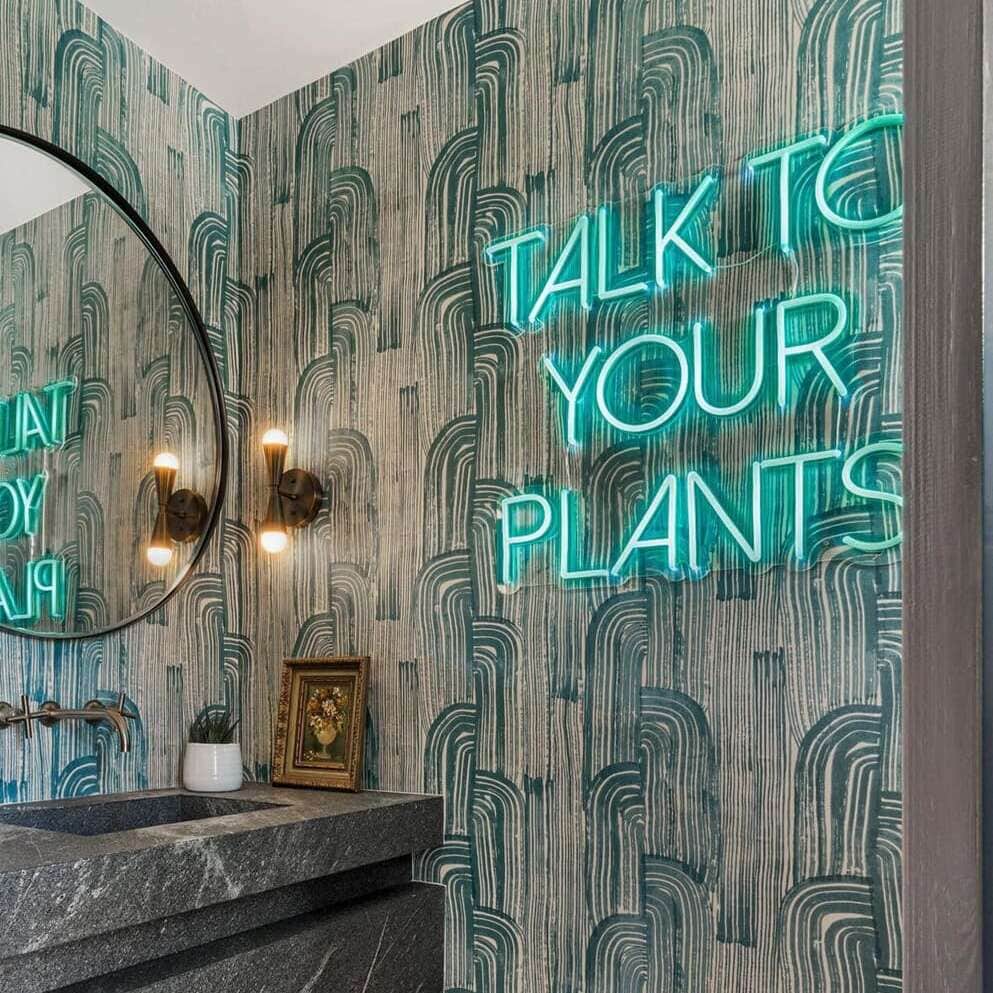 Turquoise Talk to Your Plants neon sign beside a bathroom mirror