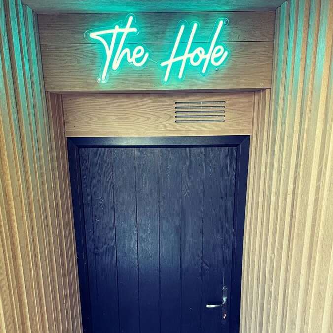 Turquoise script neon sign for a basement entrance