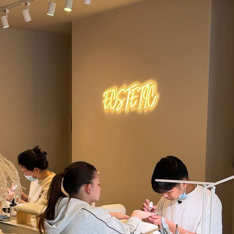 Warm white nail salon neon sign on a textured beige wall