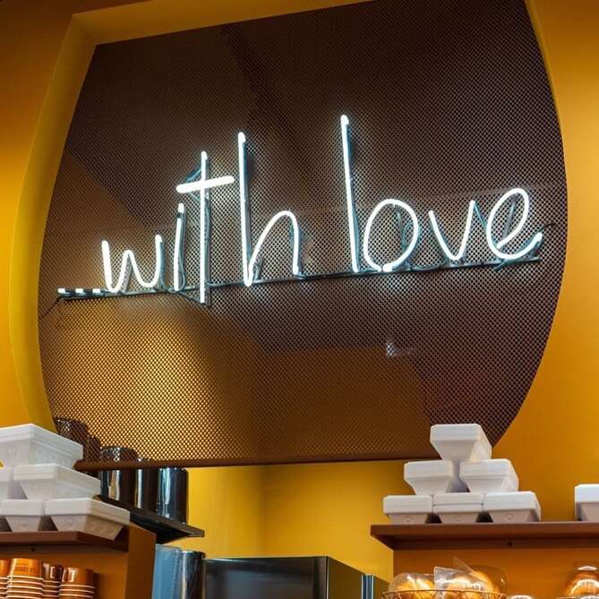 White real glass With Love neon sign above a pastry display in a dessert cafe