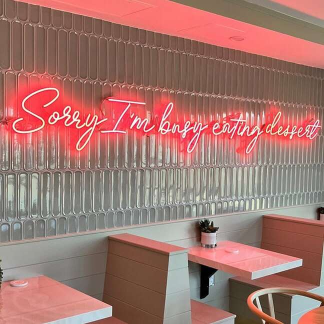 red Sorry I'm Busy Eating Dessert glass real neon sign in a dessert shop seating area